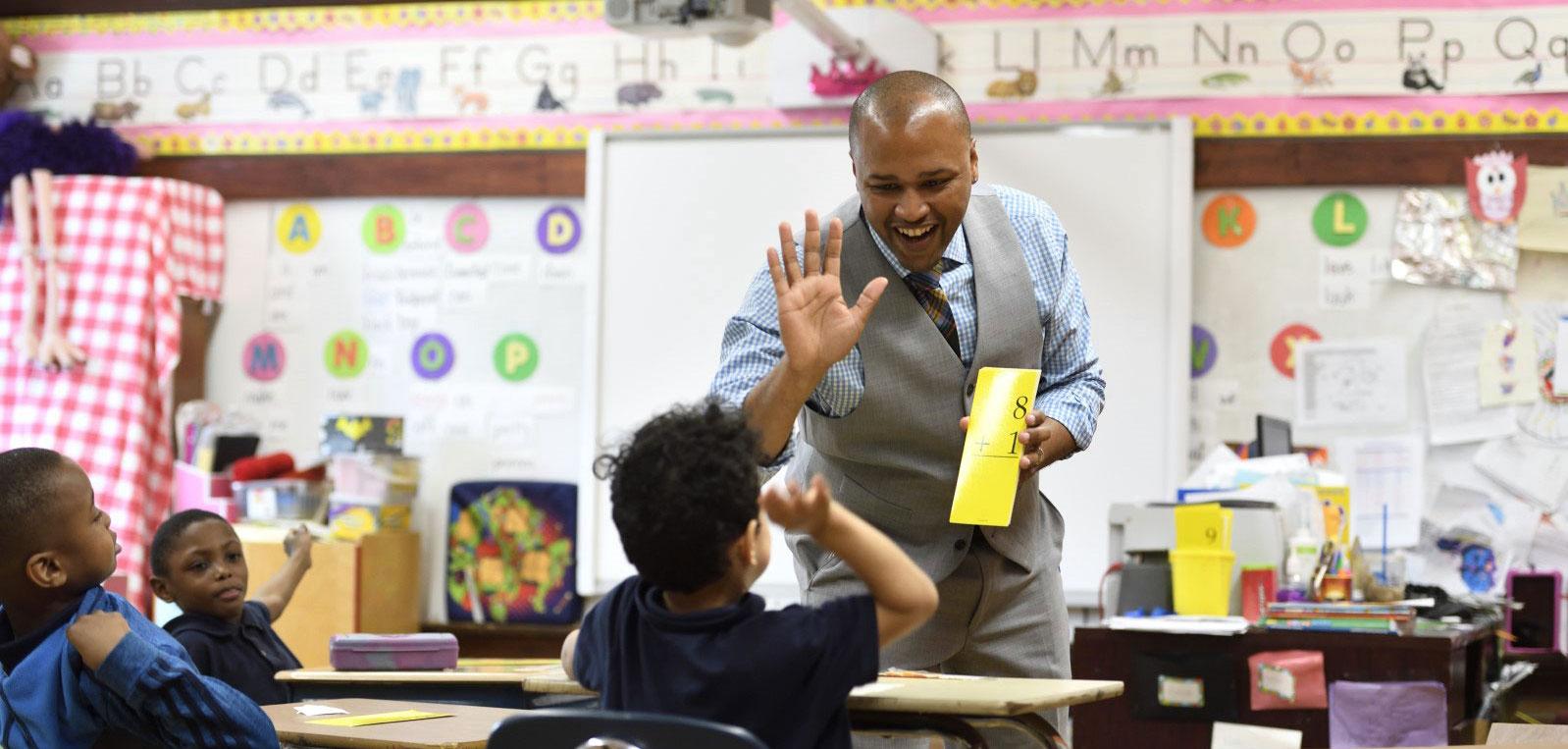 Male teacher high fiving a young student