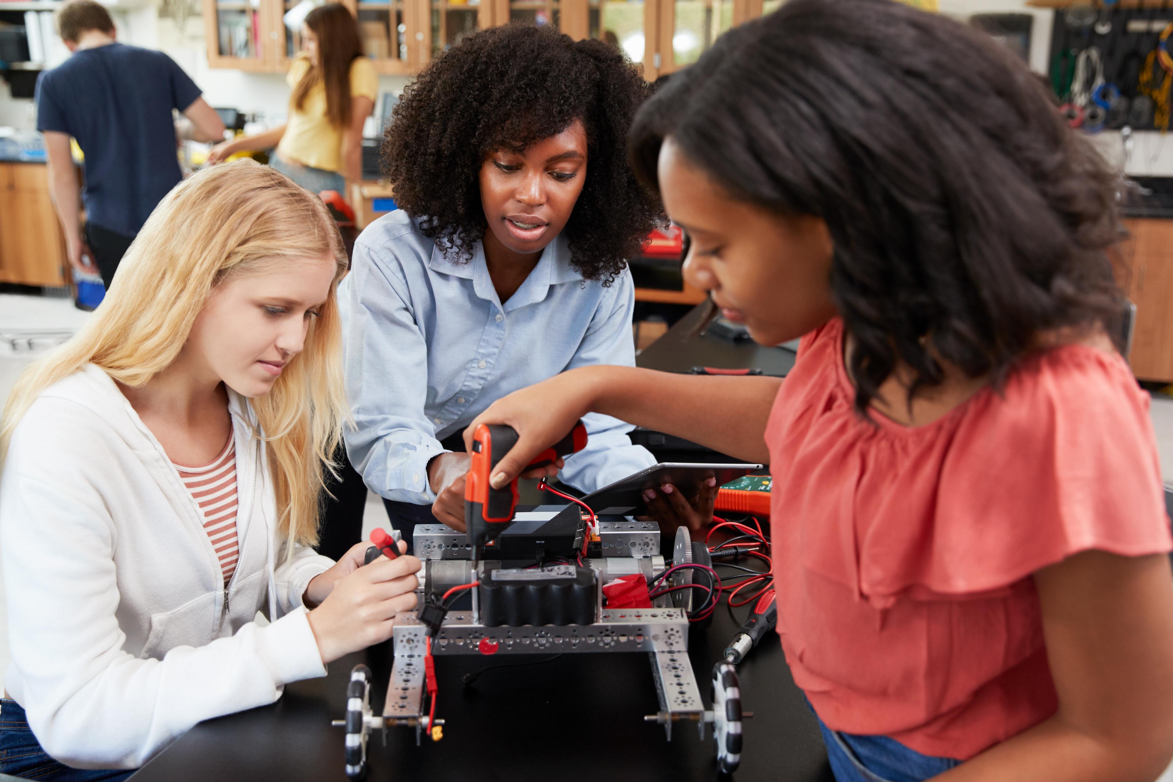 Three college students working to make a robot in a school lab.