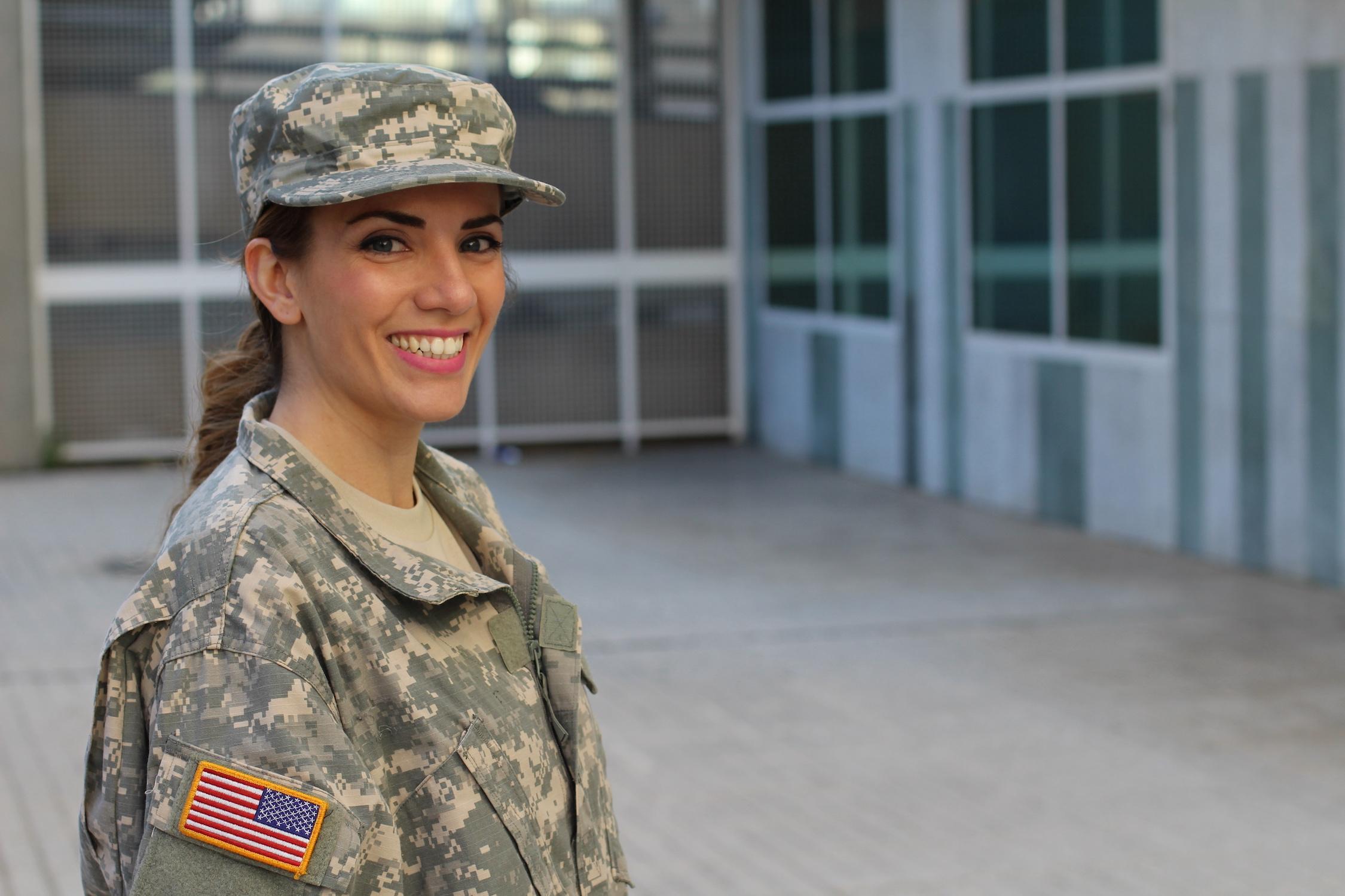 A smiling SC service member stands in the courtyard of a teaching university building.
